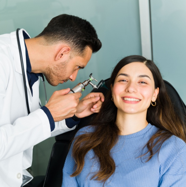 Provider examining a patient's ear with an otoscope at Elon Health Urgent Care in Davenport, FL